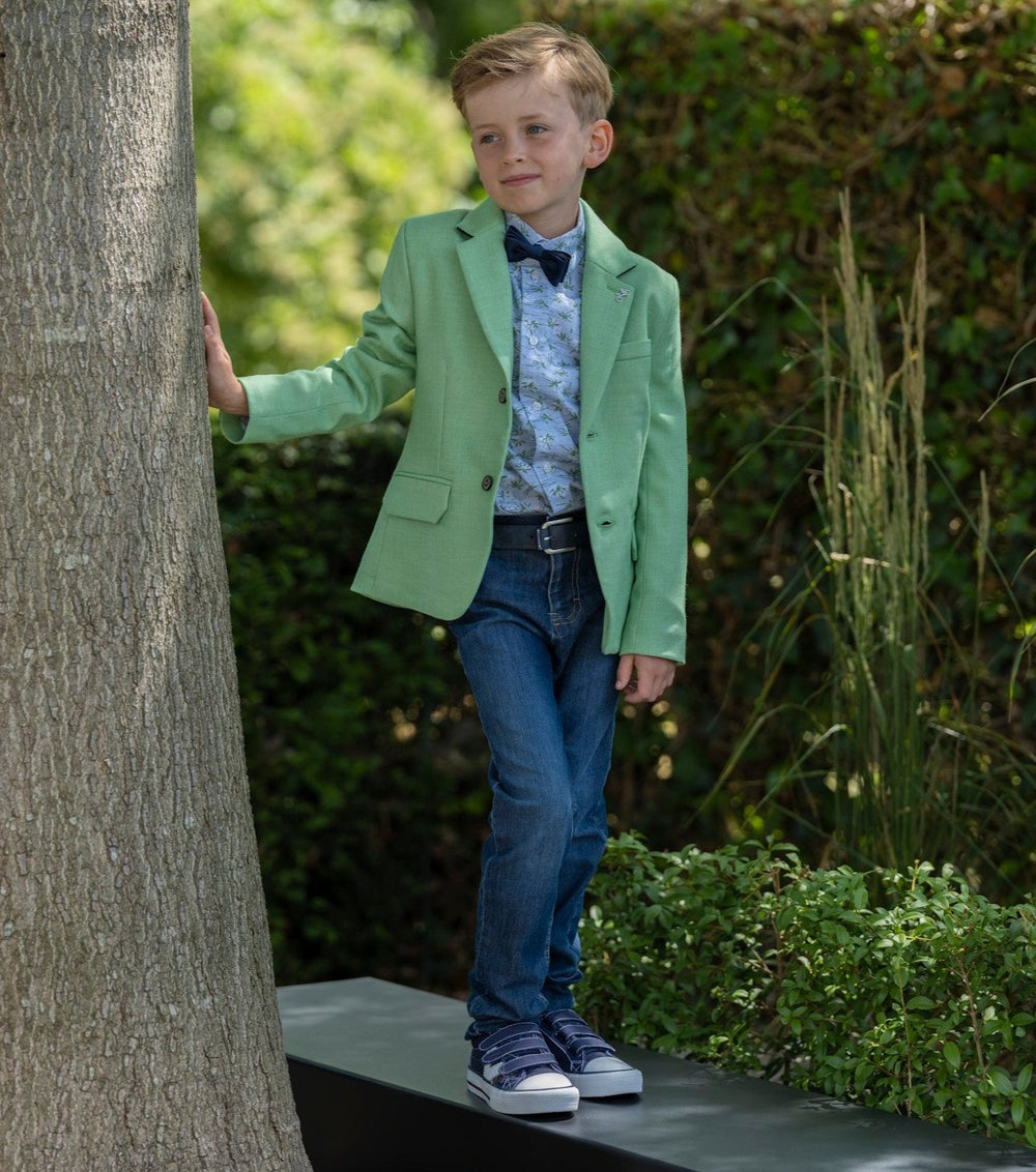 Klassieke jeanslook met groene blazer, strik en blauw hemd met print