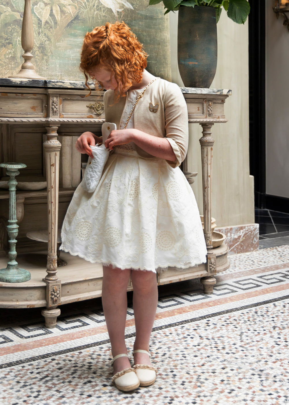 Ecru jurk in broderie anglaise en een goudkleurige cardigan